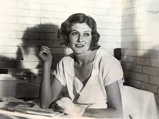 A woman sitting at a table with papers in front of her.