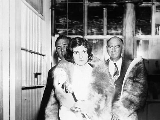 A woman in fur coat standing next to two men.