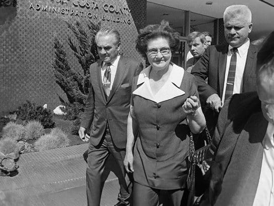 A woman in a suit and tie walking down the street.