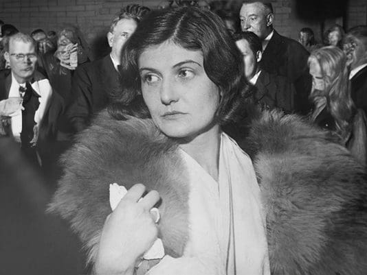 A woman in white dress and fur coat.