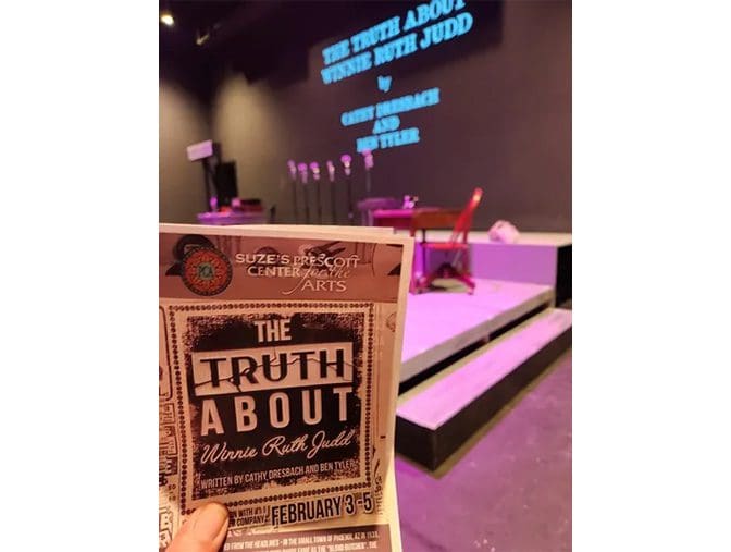 A person holding up a book in front of a stage.