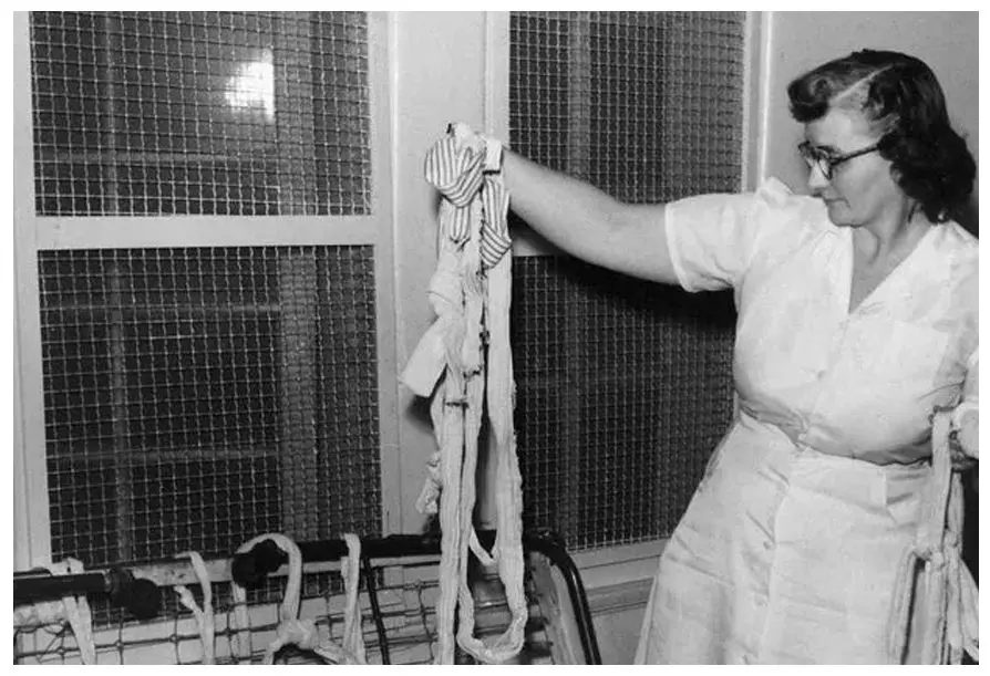 A woman holding up some ropes in front of a cage.