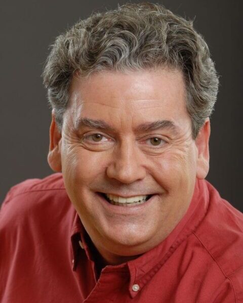 A man with grey hair and wearing red shirt.