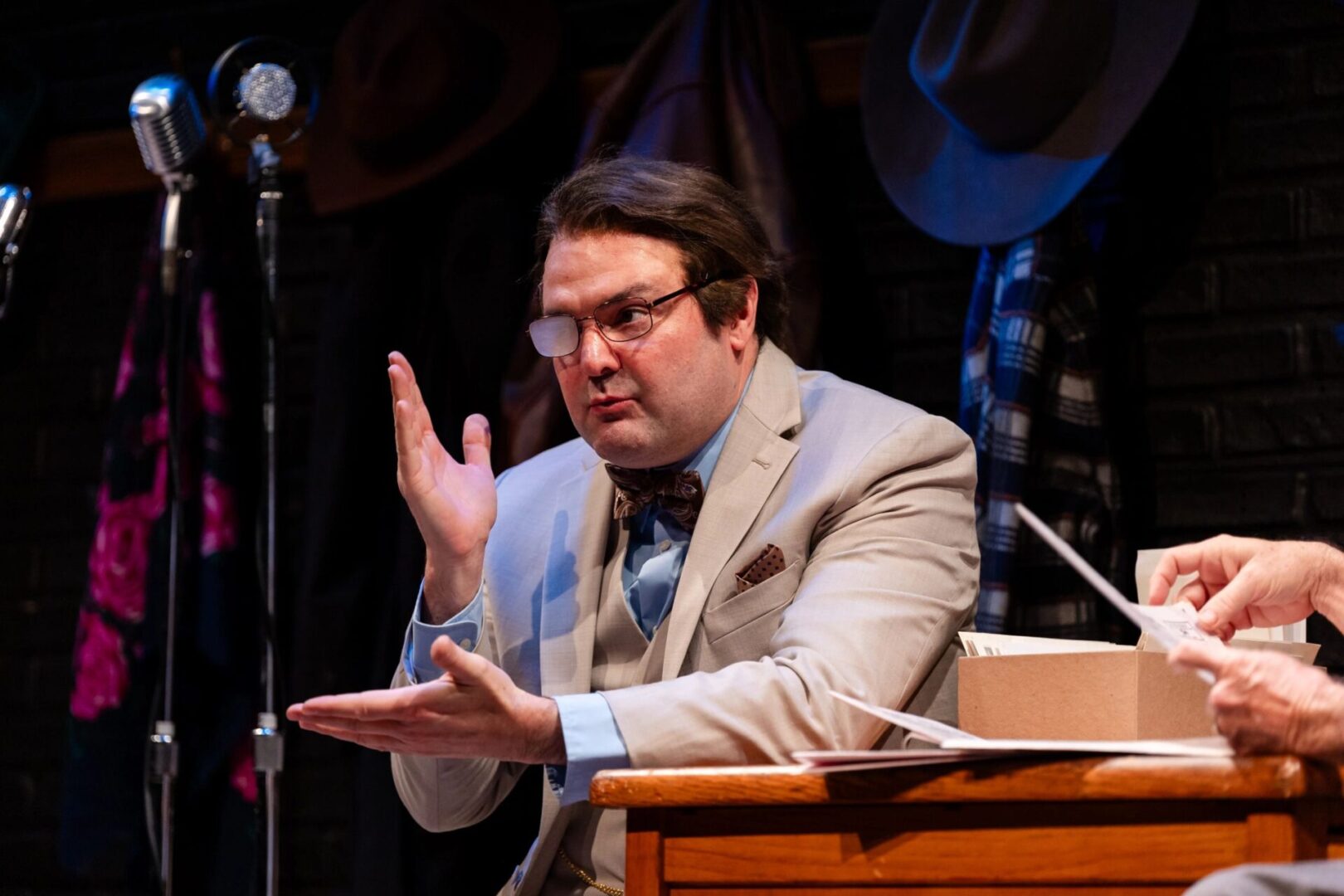 A man in suit and tie sitting at a podium.