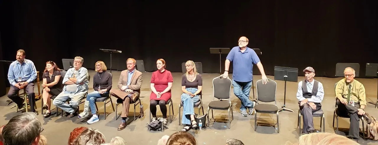 A group of people sitting on chairs in front of a microphone.