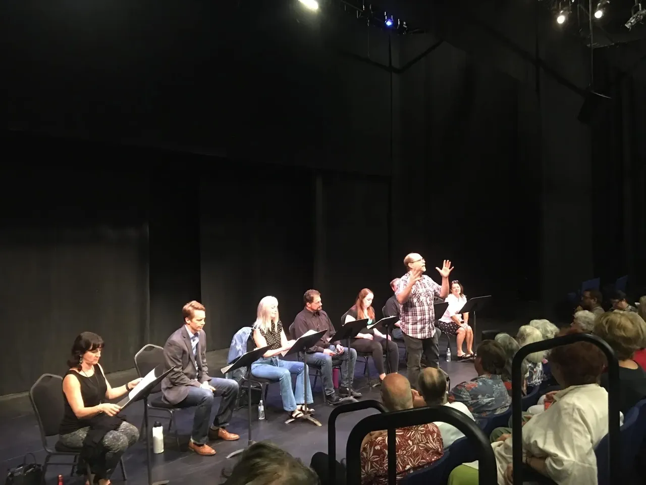 A group of people sitting on chairs in front of a stage.